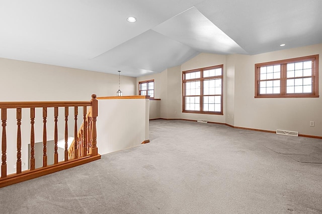 bonus room with light colored carpet and vaulted ceiling