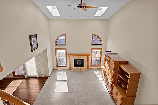 living room with a tiled fireplace, ceiling fan, dark hardwood / wood-style floors, and high vaulted ceiling