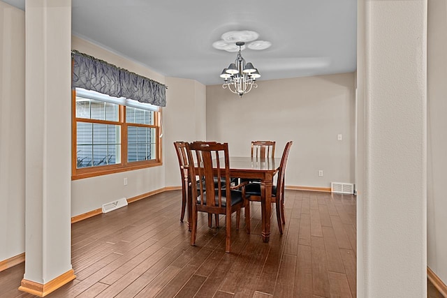 dining space featuring dark wood-type flooring and an inviting chandelier