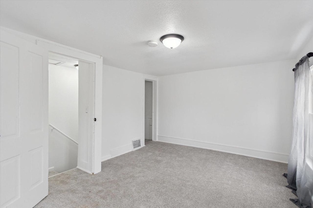 spare room with light colored carpet and a textured ceiling