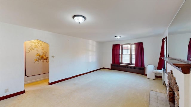 unfurnished living room with radiator heating unit and light carpet