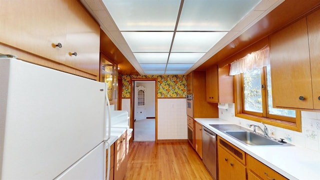 kitchen with white appliances, sink, and light wood-type flooring