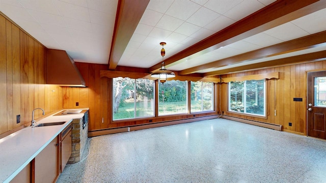 kitchen featuring pendant lighting, sink, beamed ceiling, and wood walls