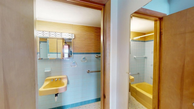 bathroom with tiled shower / bath combo, sink, tile walls, and tile patterned floors