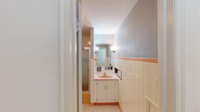 hall with sink, tile walls, and light tile patterned floors