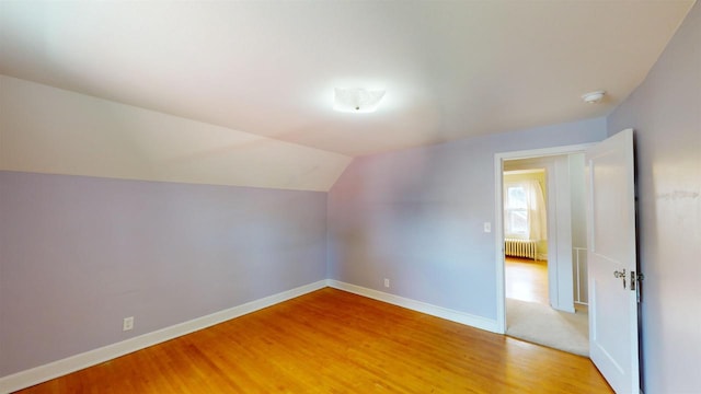 bonus room with radiator, wood-type flooring, and vaulted ceiling