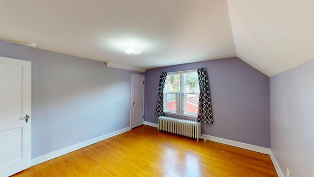 bonus room featuring radiator heating unit, vaulted ceiling, and wood-type flooring