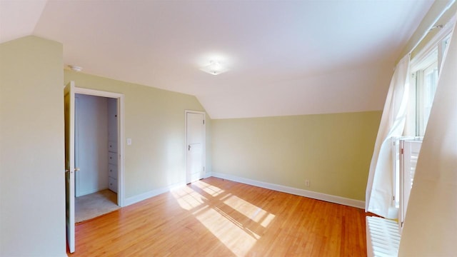 additional living space featuring lofted ceiling and light hardwood / wood-style floors