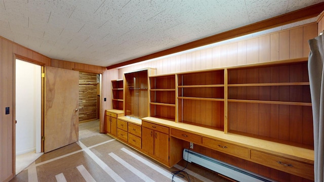 unfurnished office with a baseboard radiator, built in desk, and wood walls