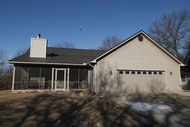W5698 Losinski Rd, Princeton, WI 54968 - back of house with a sunroom, concrete driveway, an attached garage, and a chimney