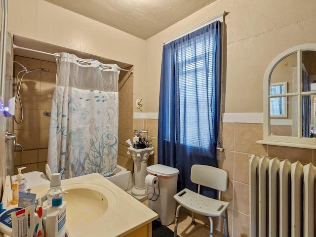 bathroom featuring radiator heating unit, shower / tub combo, tile walls, and vanity