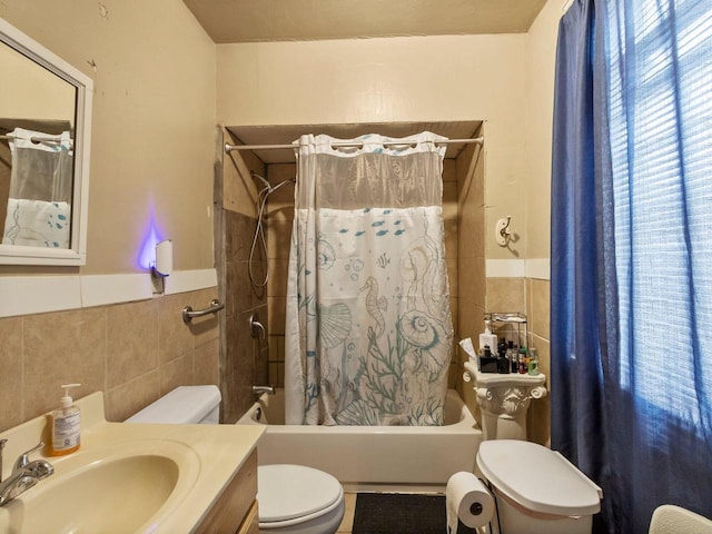 full bathroom featuring toilet, shower / bathtub combination with curtain, sink, and tile walls