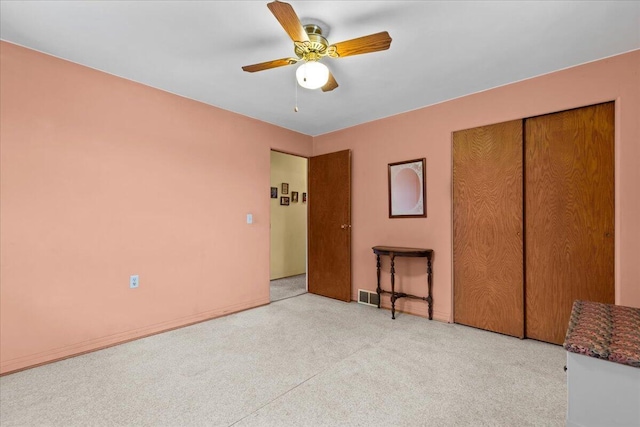 unfurnished bedroom featuring ceiling fan, light colored carpet, and a closet