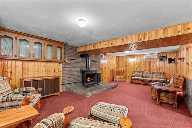 living room featuring carpet flooring, a wood stove, a textured ceiling, and wooden walls