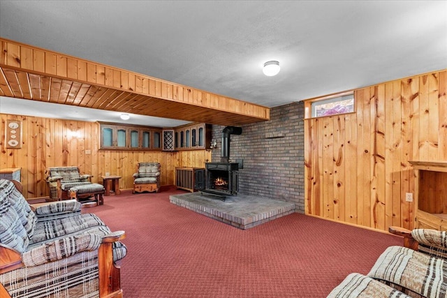 carpeted living room with a wood stove and wooden walls