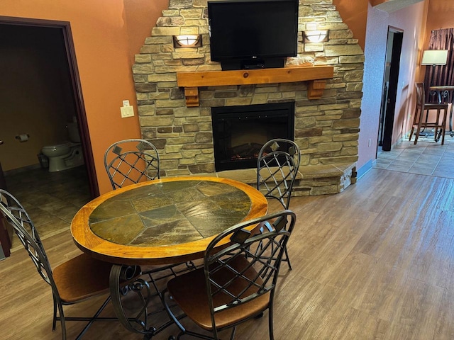 dining room with a stone fireplace and wood-type flooring