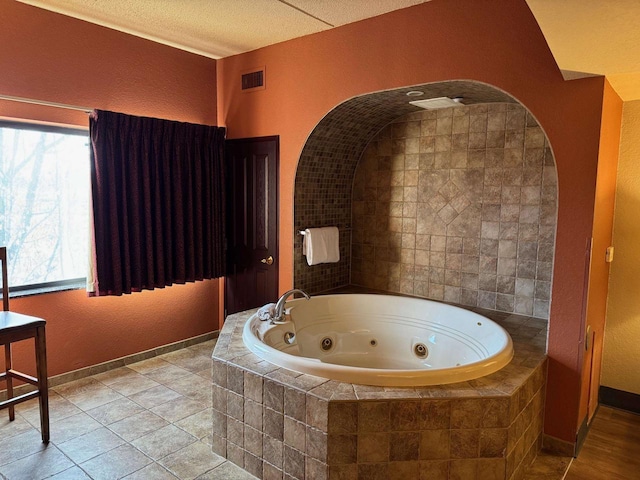 bathroom featuring tile patterned floors, a textured ceiling, and tiled tub