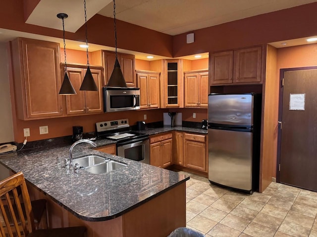 kitchen featuring pendant lighting, sink, stainless steel appliances, kitchen peninsula, and dark stone counters