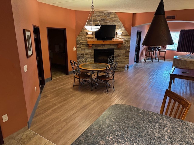 dining room with hardwood / wood-style floors, a textured ceiling, and a fireplace