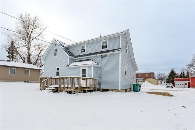 snow covered rear of property with a deck