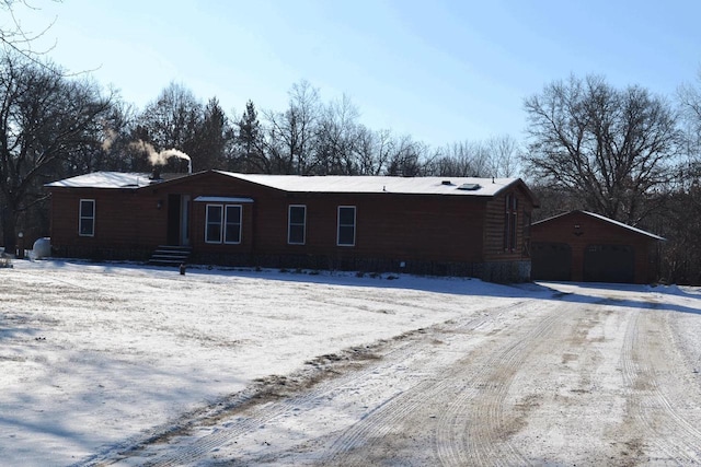 snow covered house featuring a garage and an outdoor structure