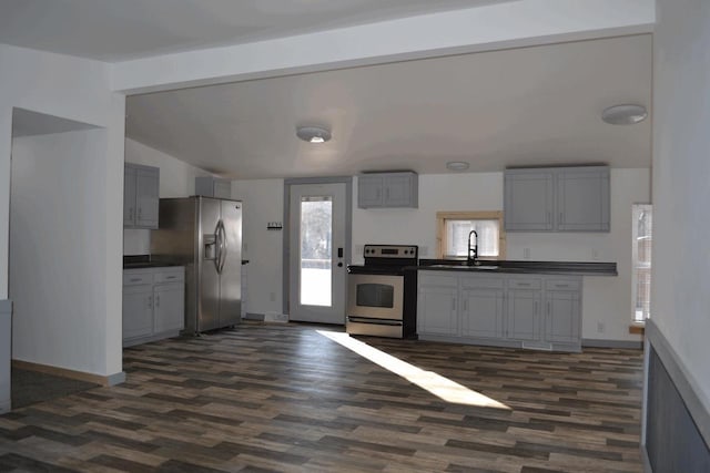 kitchen featuring appliances with stainless steel finishes, lofted ceiling with beams, sink, gray cabinetry, and dark hardwood / wood-style flooring