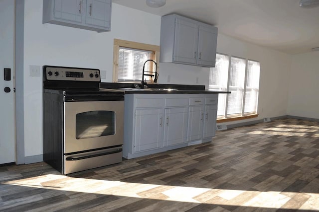 kitchen with sink, electric range, dark wood-type flooring, and white cabinets