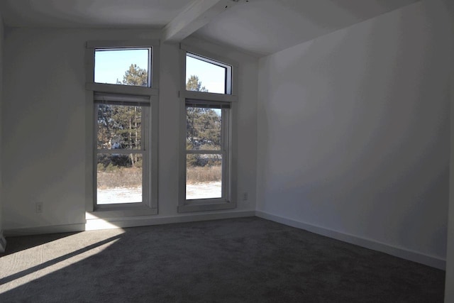 spare room with plenty of natural light, beam ceiling, and dark carpet