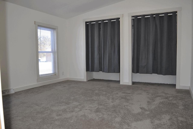 empty room featuring vaulted ceiling and dark carpet