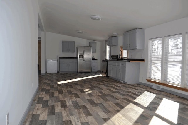 kitchen with lofted ceiling, sink, gray cabinetry, dark hardwood / wood-style floors, and stainless steel refrigerator with ice dispenser