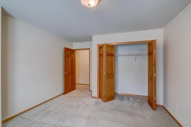 unfurnished bedroom featuring light carpet and a closet