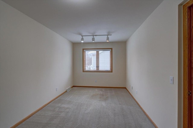 empty room with light colored carpet and track lighting