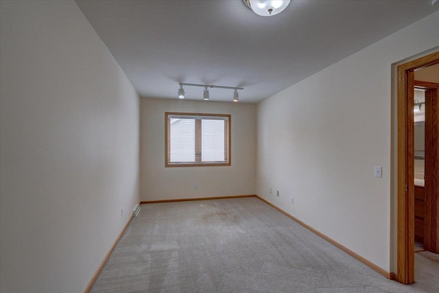 carpeted spare room featuring track lighting