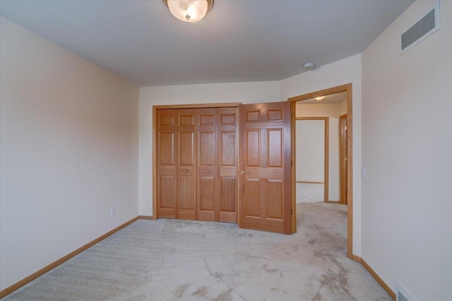 unfurnished bedroom featuring light colored carpet and a closet