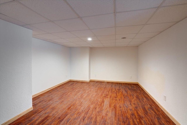 empty room with a drop ceiling and wood-type flooring