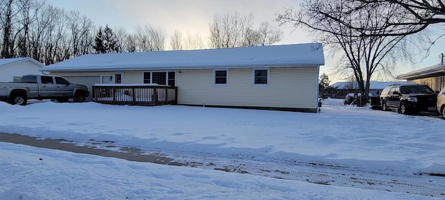 snow covered rear of property with a deck