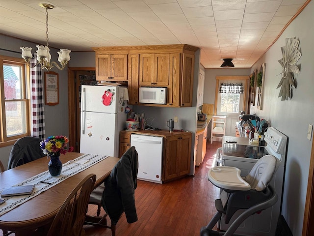 kitchen with dark hardwood / wood-style floors, an inviting chandelier, white appliances, and decorative light fixtures