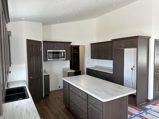 kitchen with dark brown cabinetry, dark hardwood / wood-style floors, sink, and a kitchen island