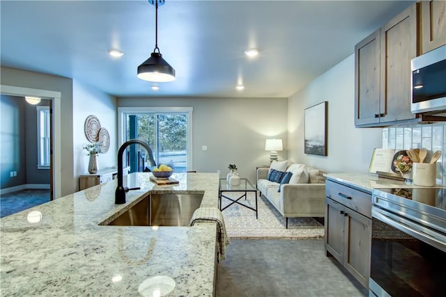 kitchen featuring pendant lighting, sink, light stone counters, and stainless steel appliances