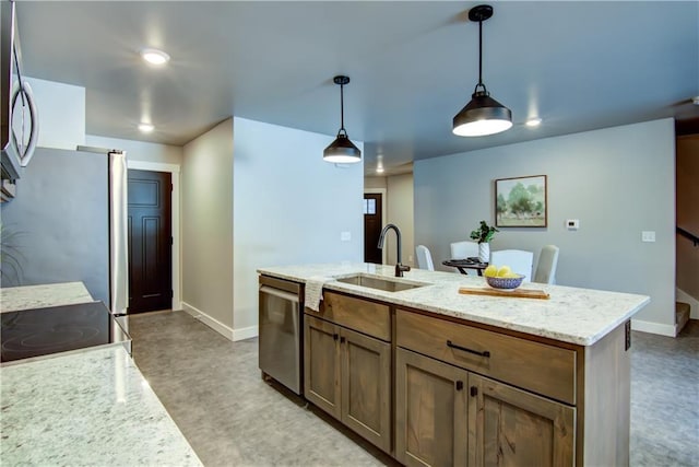 kitchen featuring appliances with stainless steel finishes, pendant lighting, sink, a kitchen island with sink, and light stone countertops