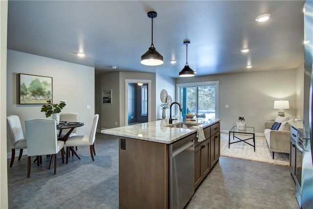 kitchen featuring sink, decorative light fixtures, a center island with sink, dishwasher, and light stone countertops