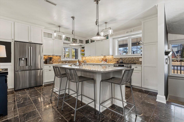 kitchen featuring stainless steel fridge, a kitchen breakfast bar, a kitchen island, and white cabinets