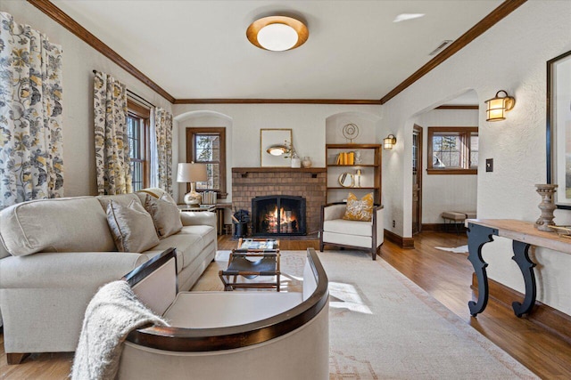 living room featuring crown molding, light hardwood / wood-style floors, and a brick fireplace