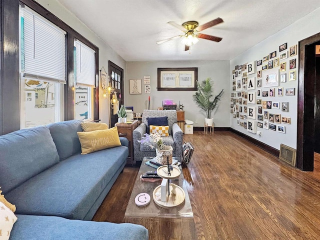 living room featuring dark wood-type flooring and ceiling fan