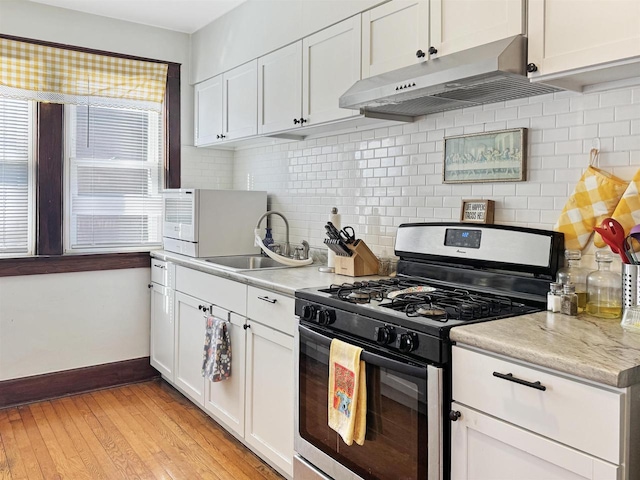 kitchen featuring sink, tasteful backsplash, stainless steel range with gas stovetop, light hardwood / wood-style floors, and white cabinets