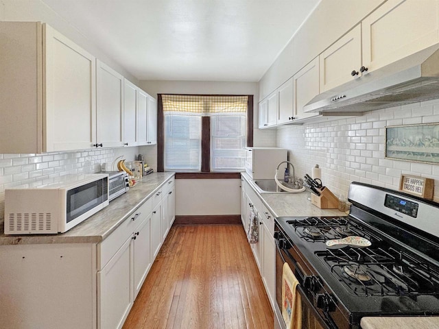 kitchen featuring white cabinetry, stainless steel gas range, tasteful backsplash, and light wood-type flooring