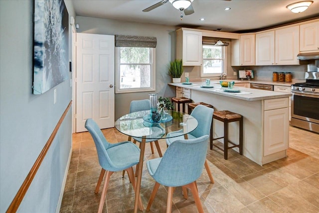 kitchen featuring sink, a breakfast bar area, ceiling fan, white cabinets, and stainless steel range with gas cooktop