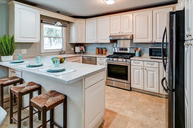 kitchen featuring appliances with stainless steel finishes, a kitchen bar, kitchen peninsula, and white cabinets