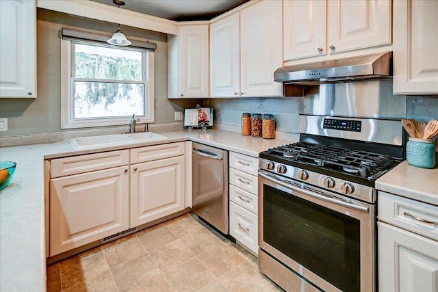 kitchen featuring appliances with stainless steel finishes, sink, white cabinets, and decorative light fixtures