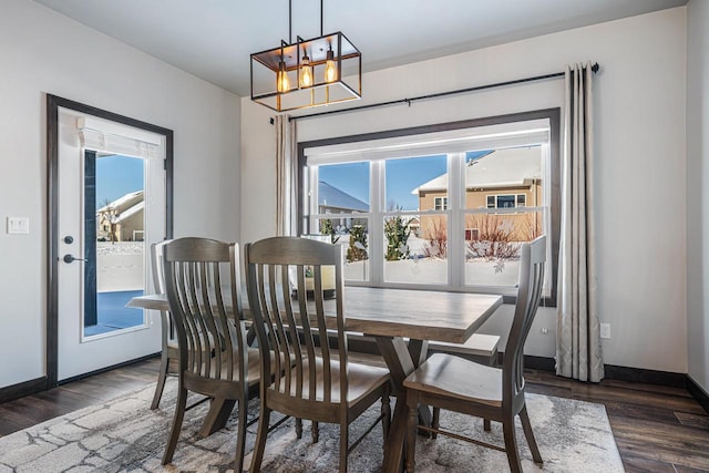 dining space featuring dark wood-type flooring and a notable chandelier